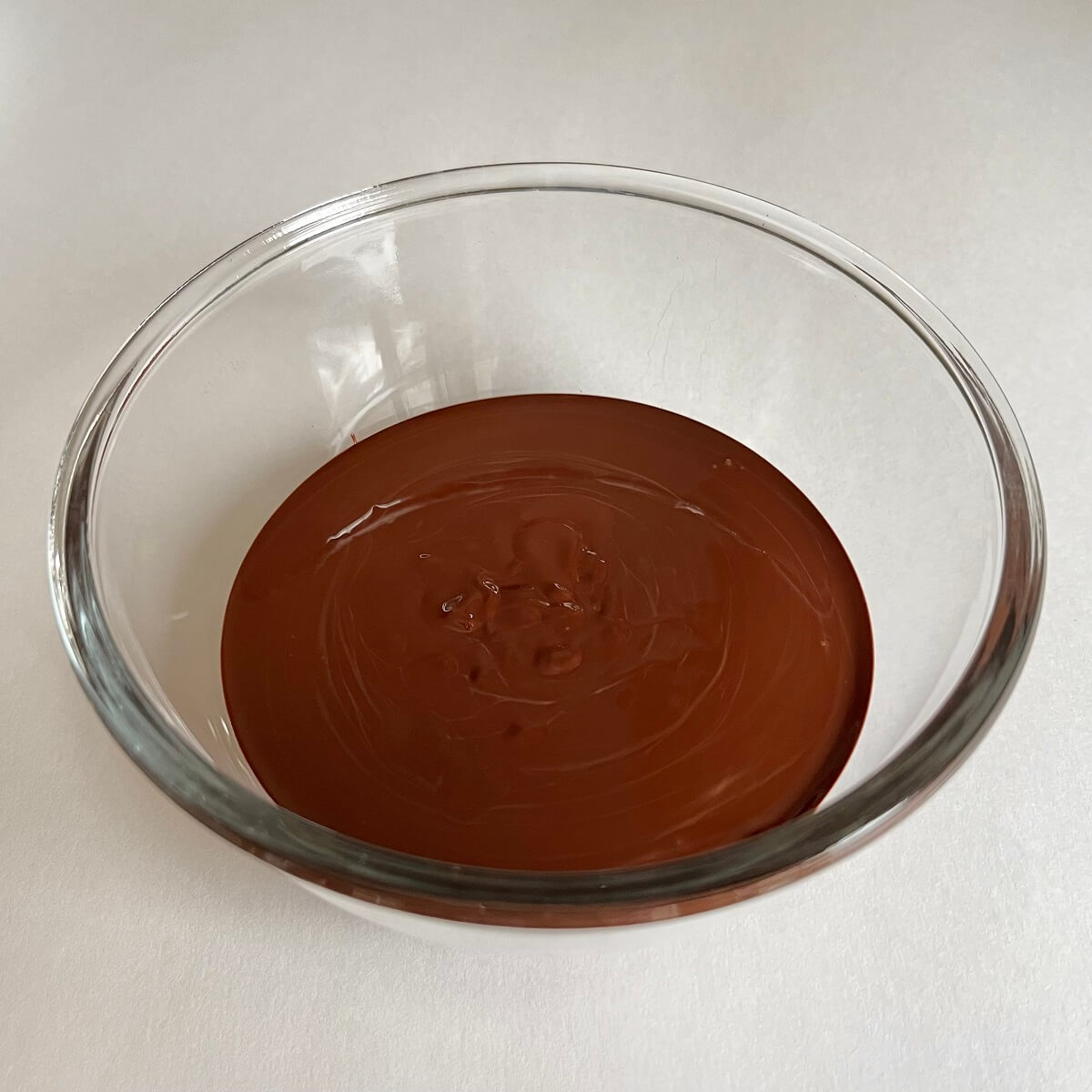 A glass bowl of warm melted dark chocolate.
