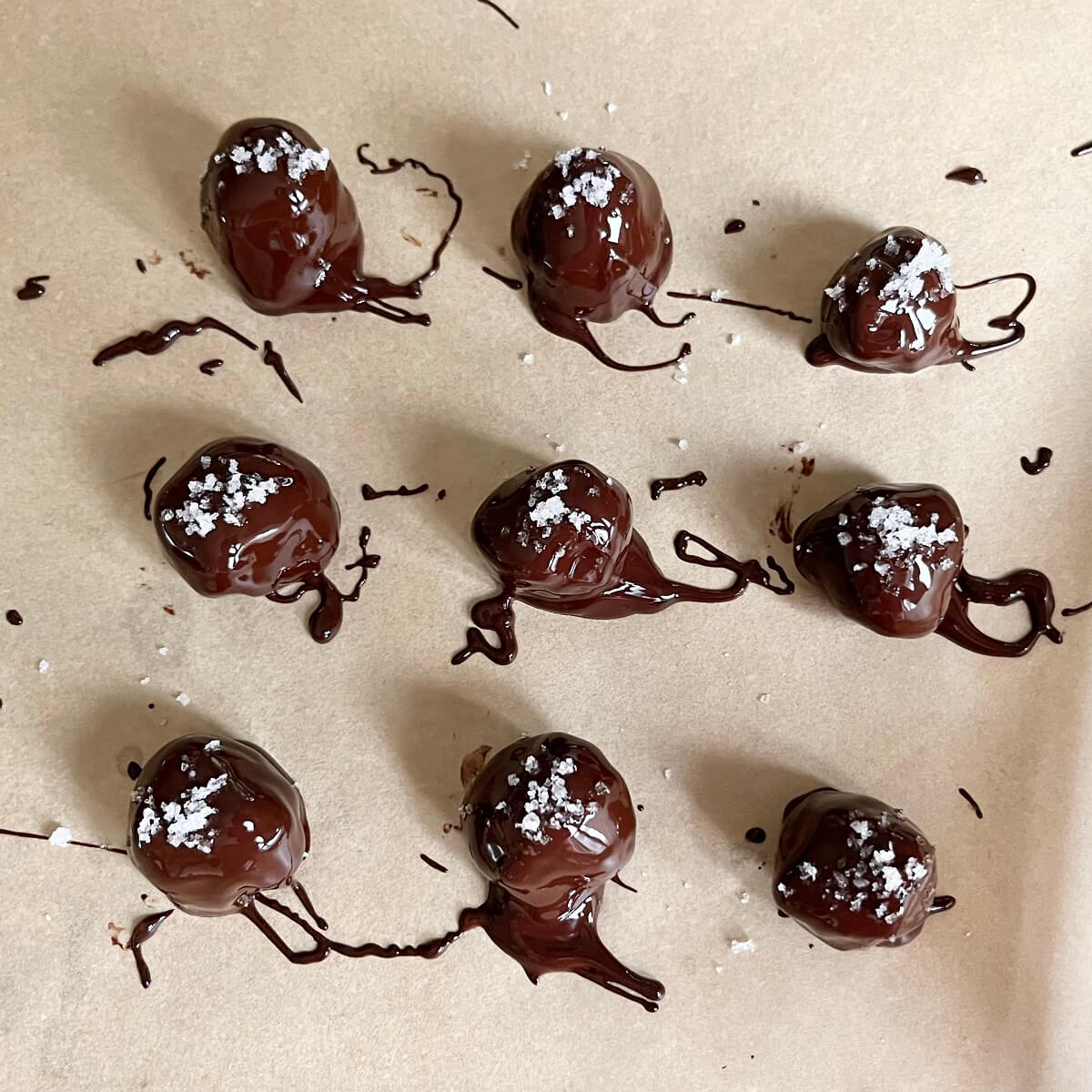 Chocolate truffles drying on a piece of parchment paper.