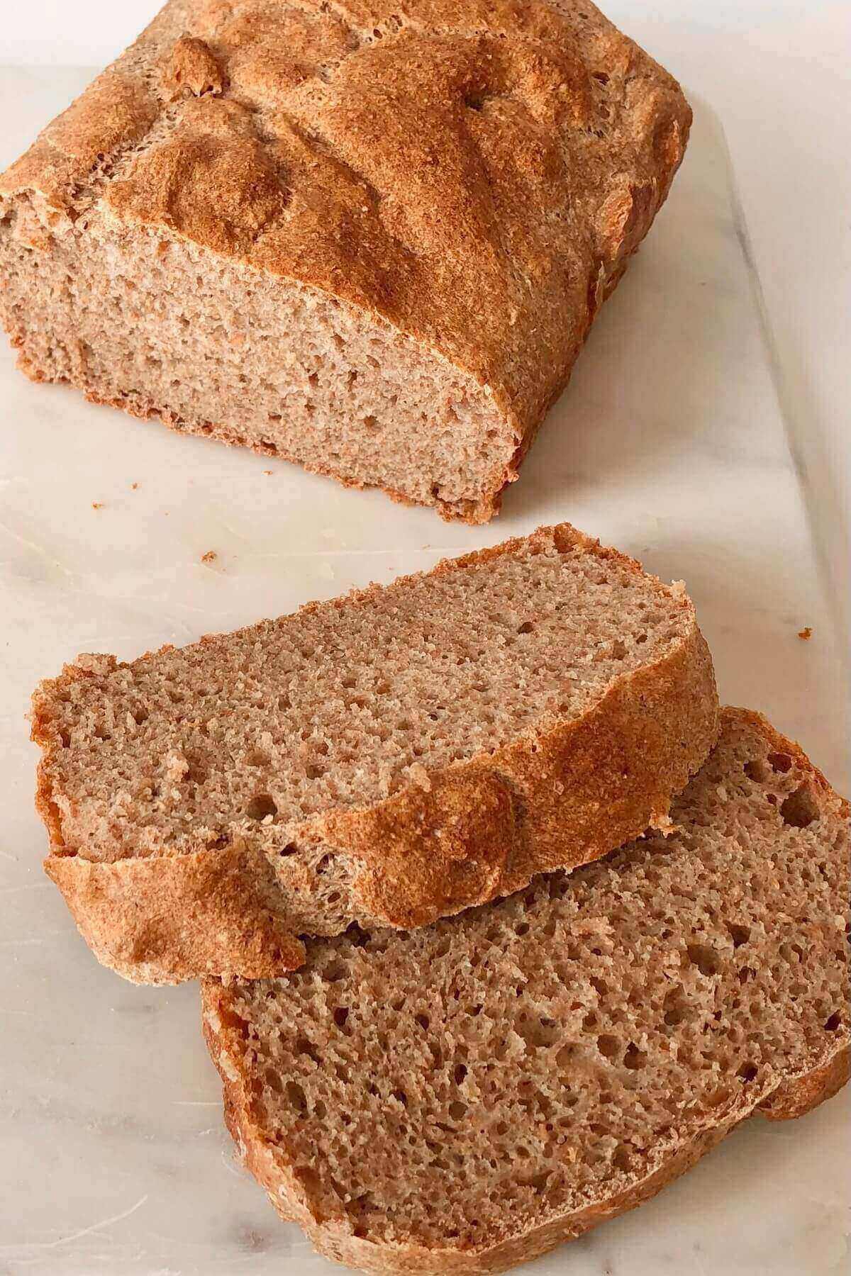 A loaf of homemade whole wheat bread with two slices cut.