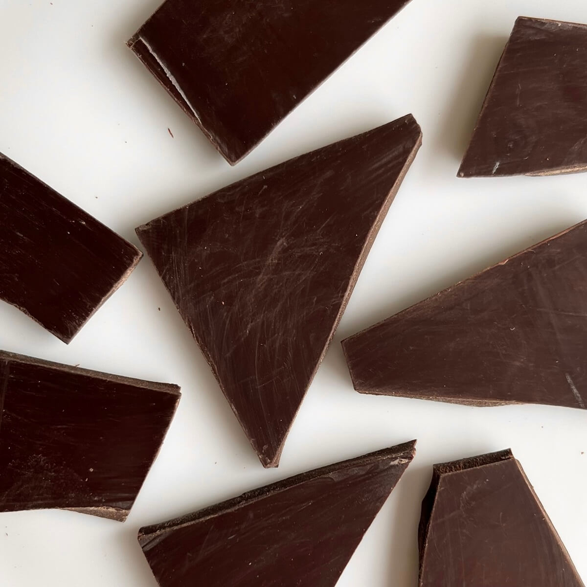 Shards of dark chocolate on a white plate.