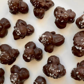 Chocolate coated hazelnut clusters on a white plate.
