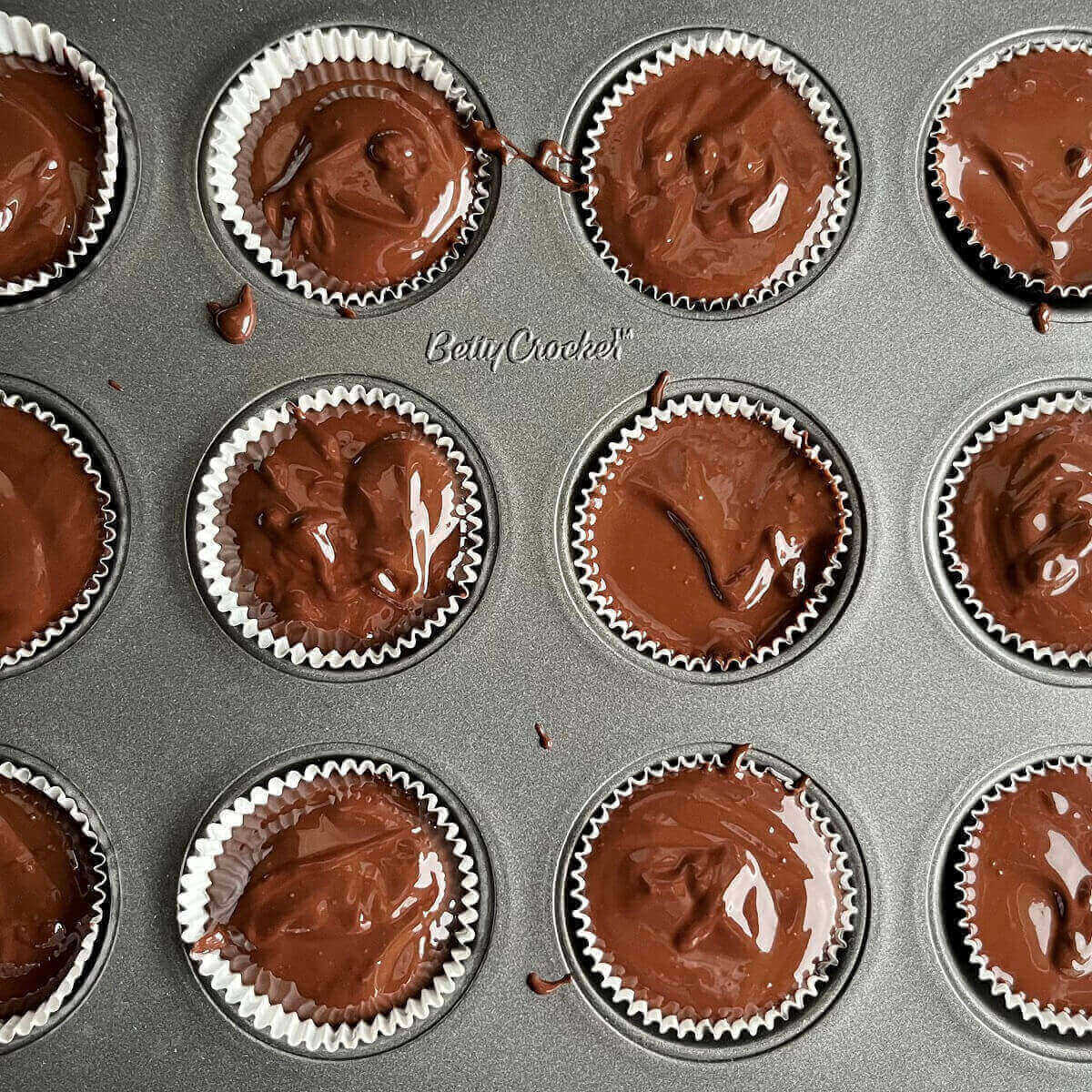 Melted chocolate peanut butter cups in a mini muffin pan.