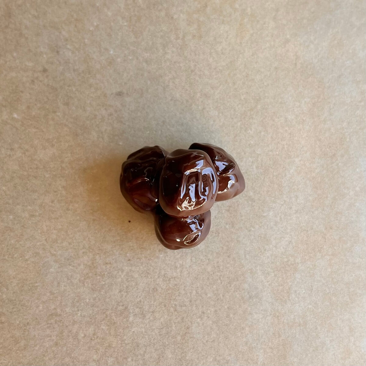 A dark chocolate hazelnut cluster on a sheet pan lined with parchment paper.