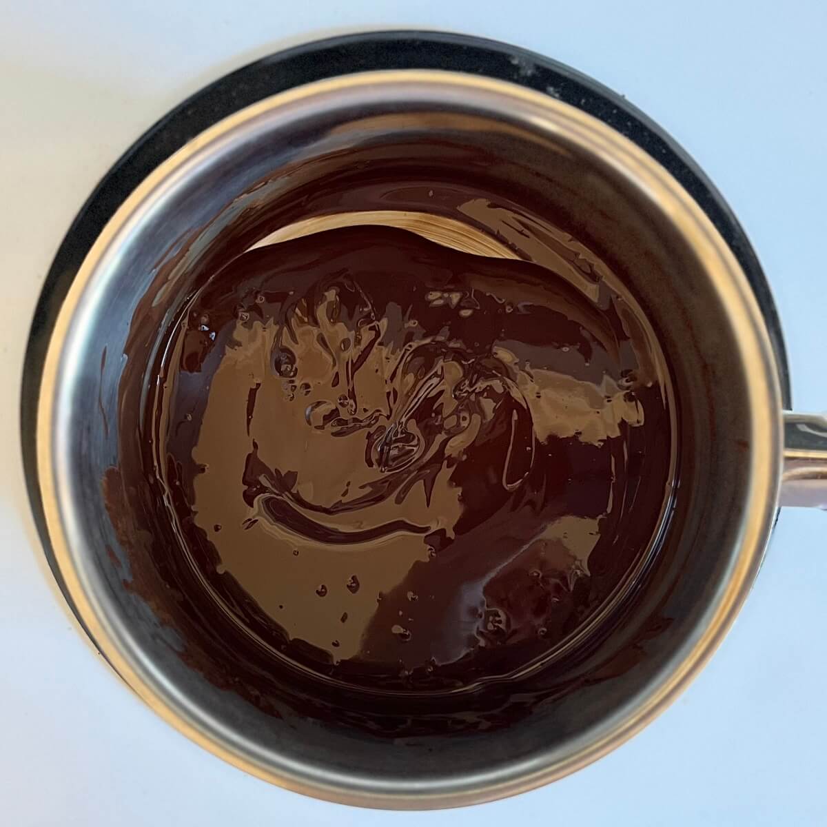Warm melted dark chocolate in a steel pot.