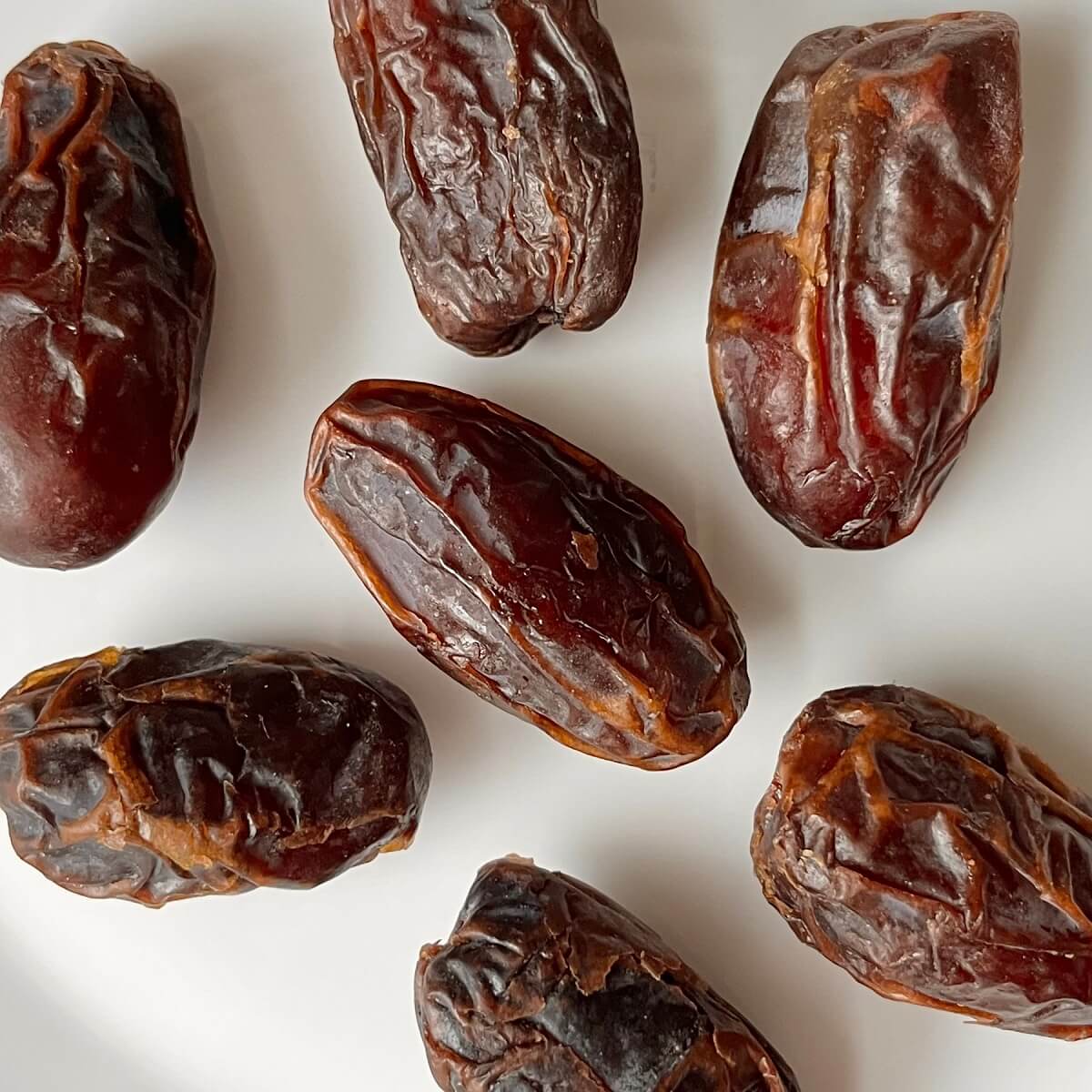 Plump, sweet Medjool dates on a white plate.