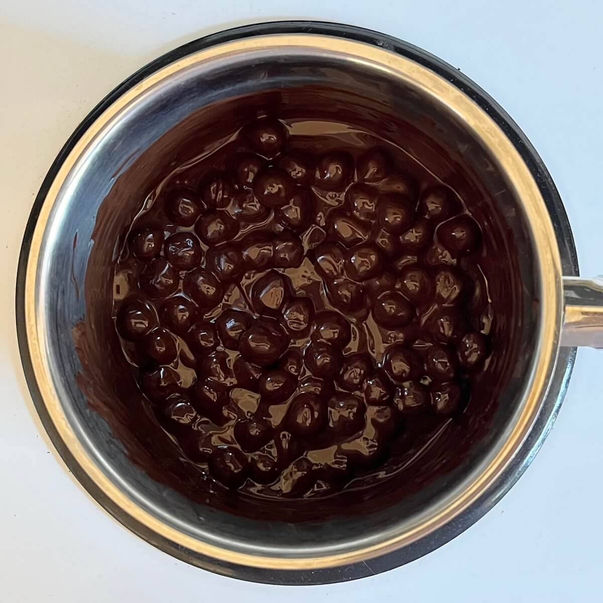 Hazelnuts and melted dark chocolate in a pot.