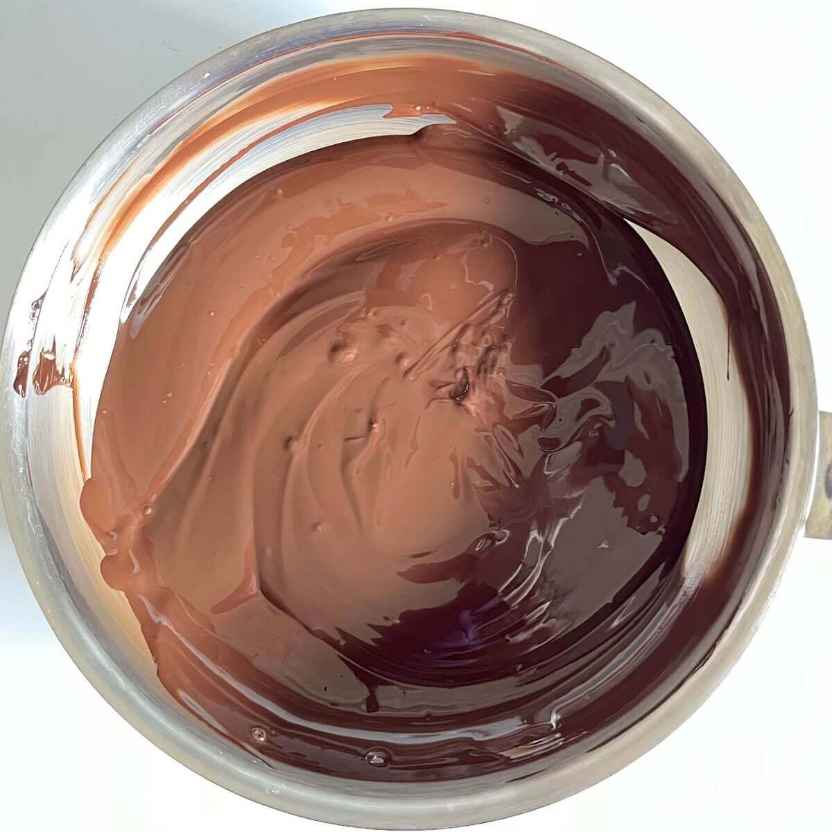 Melted dark chocolate in a stainless steel pan.