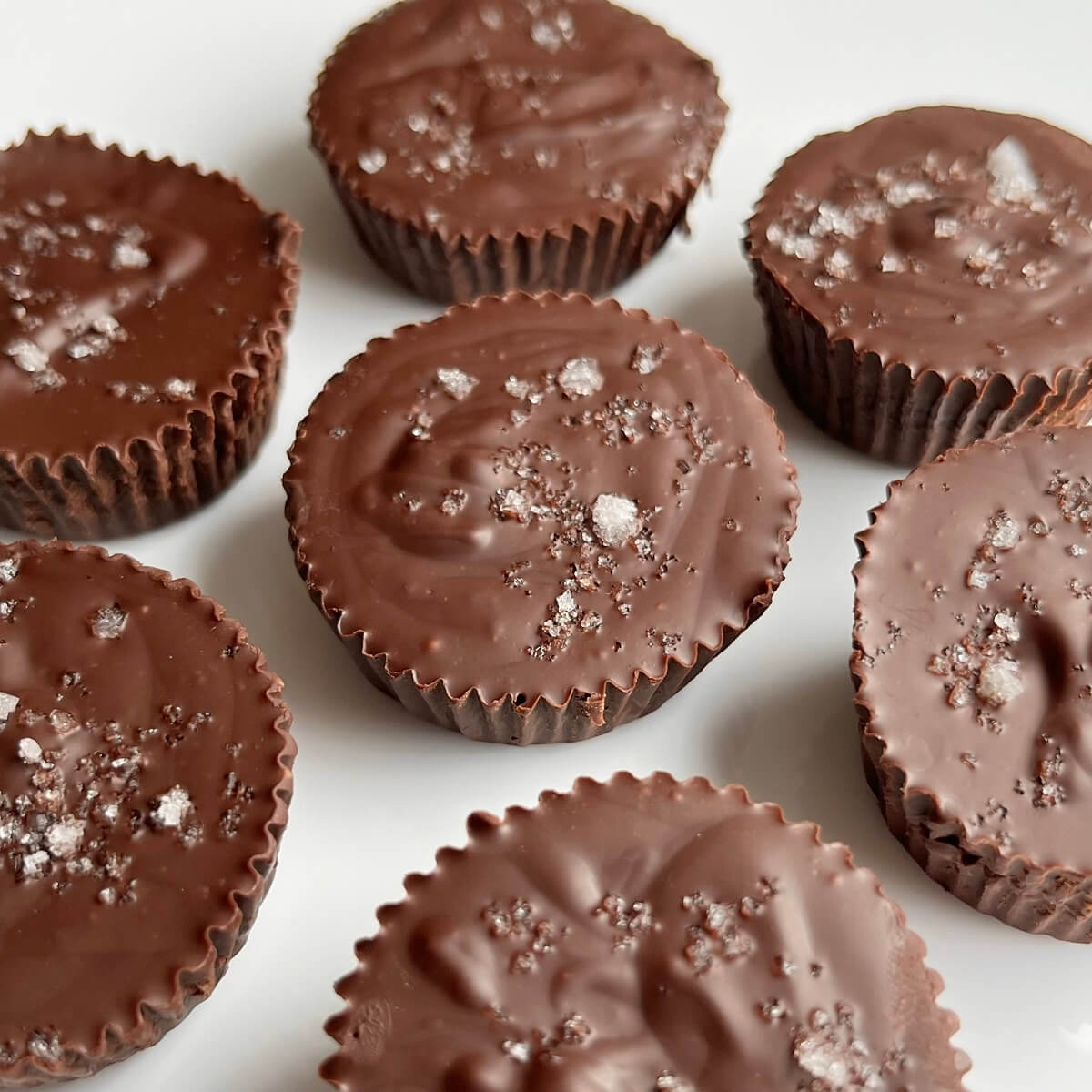 Peanut butter chocolates sprinkled with sea salt on a white plate.