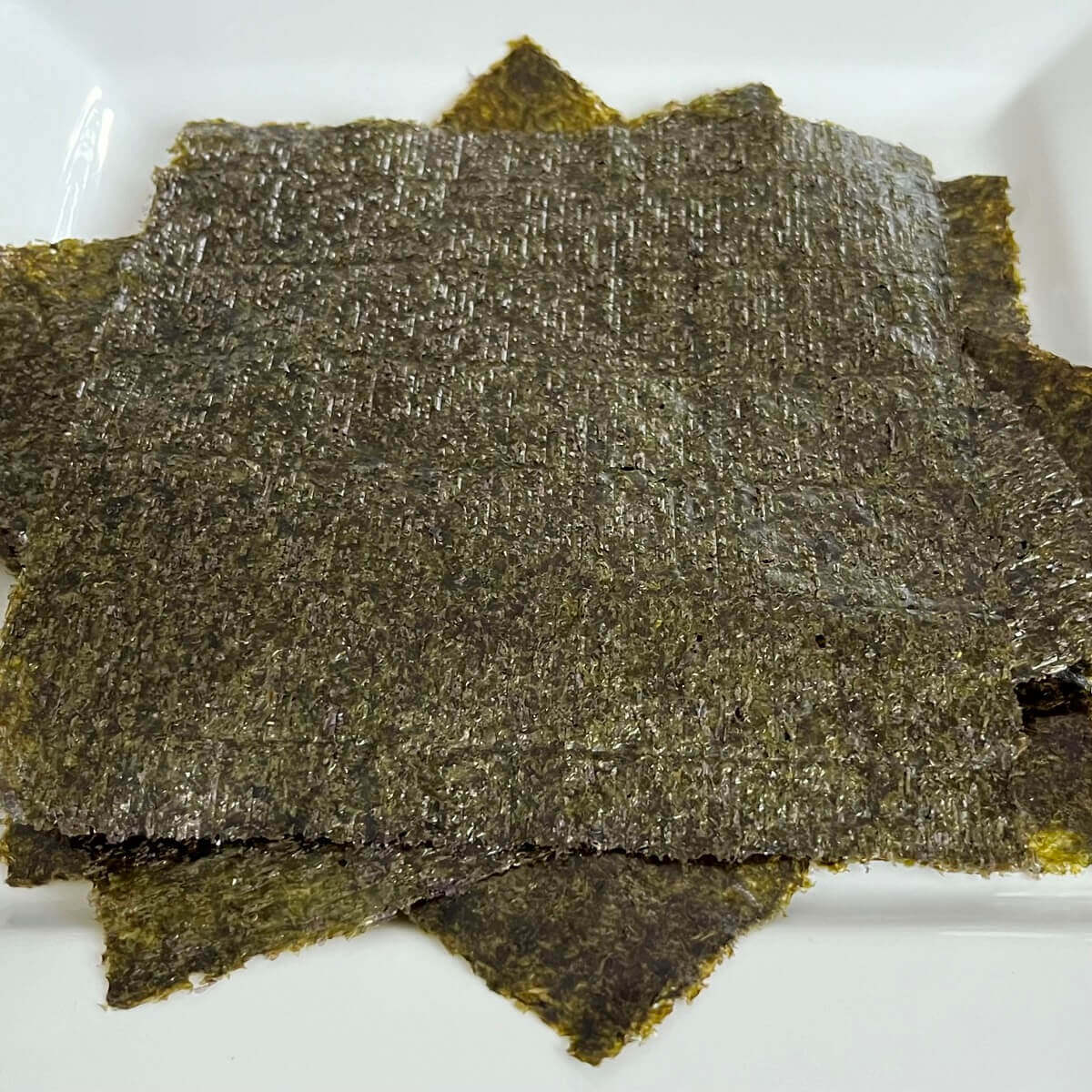 Sheets of iodine-rich, nori seaweed piled on a white plate.