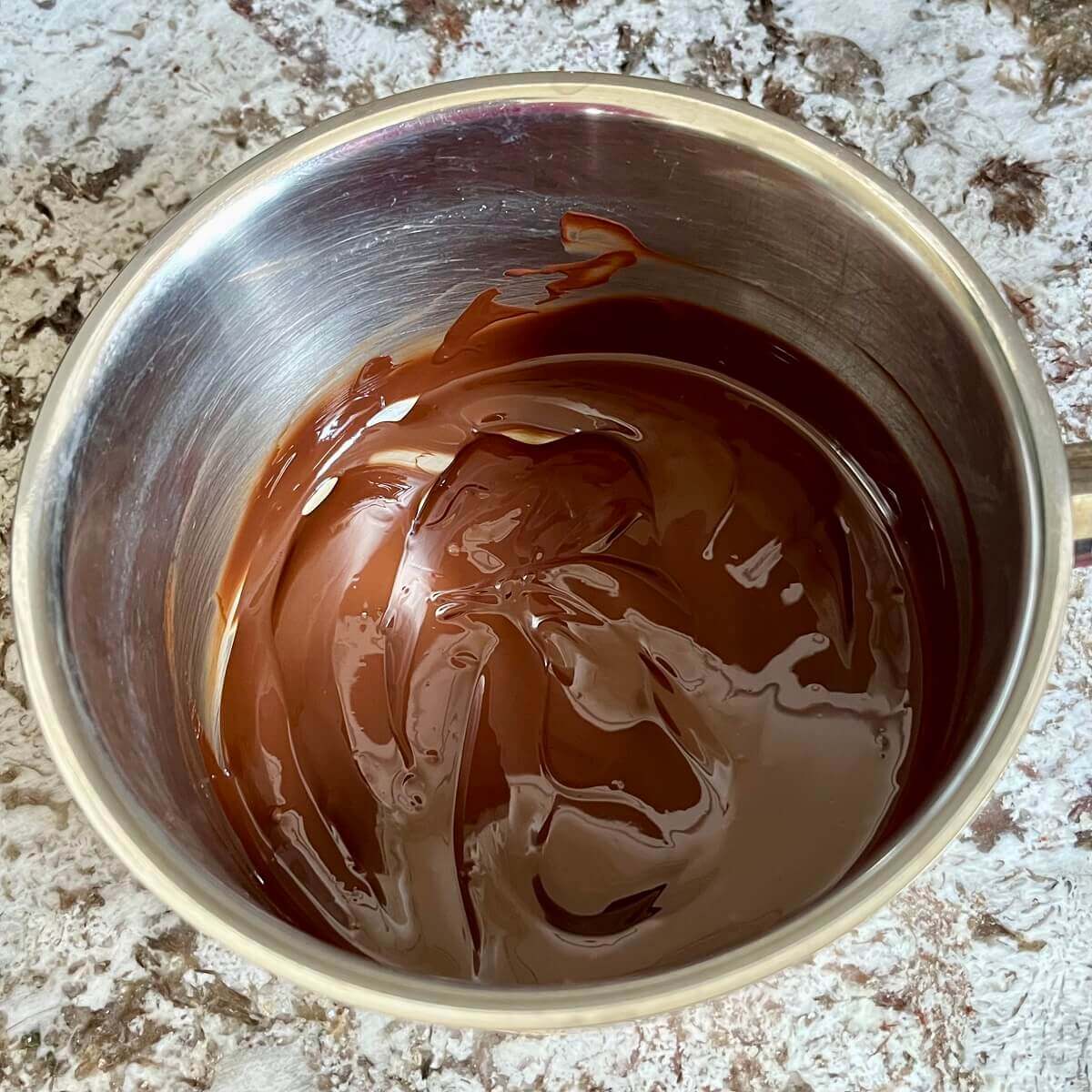Melted dark chocolate in a steel pot.