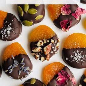 Chocolate dipped apricots on a white plate.