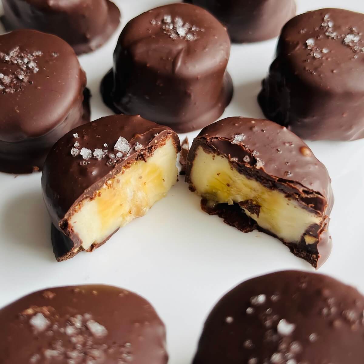 Chocolate covered banana slices on a white plate.