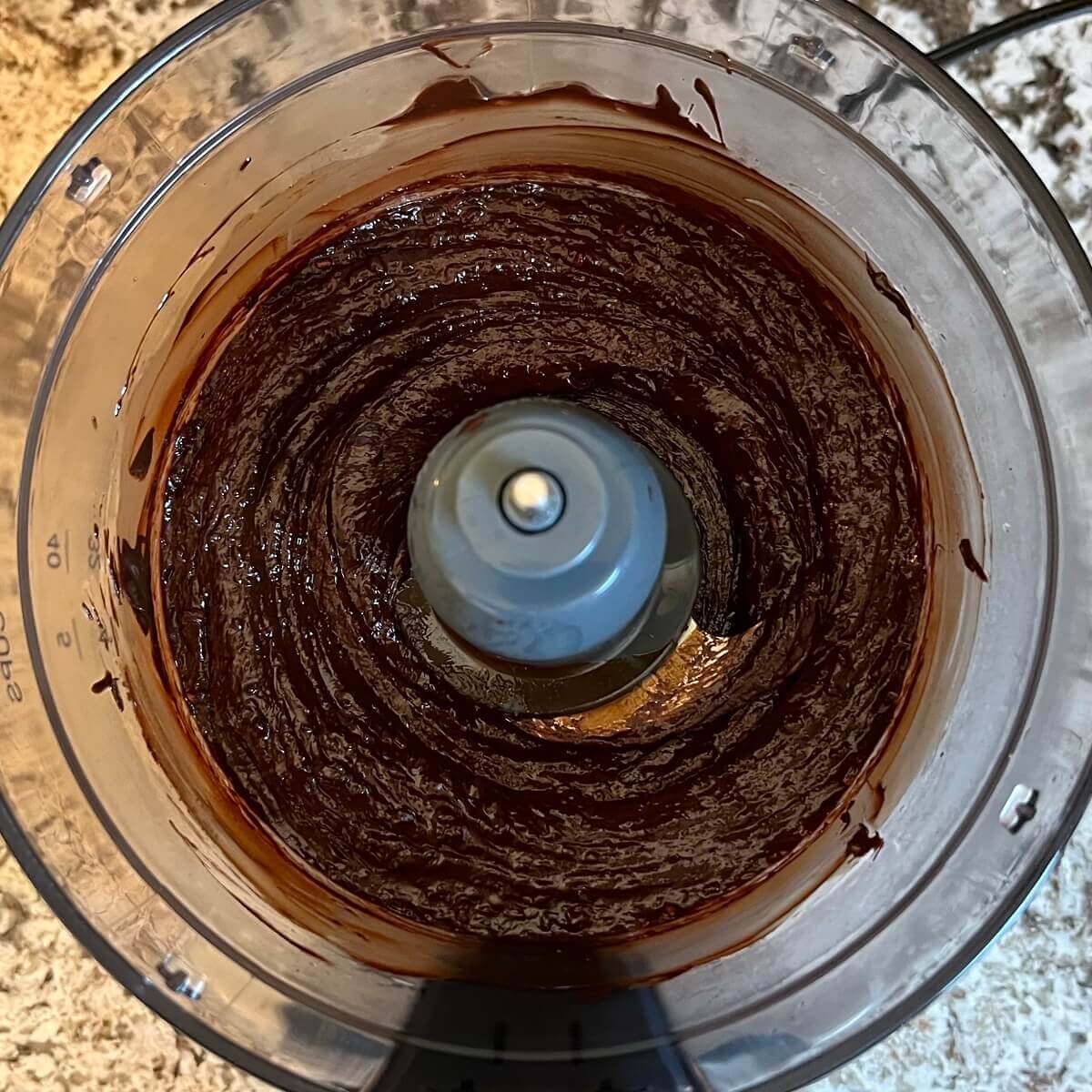 A blended mixture of melted chocolate and raspberries in a food processor.