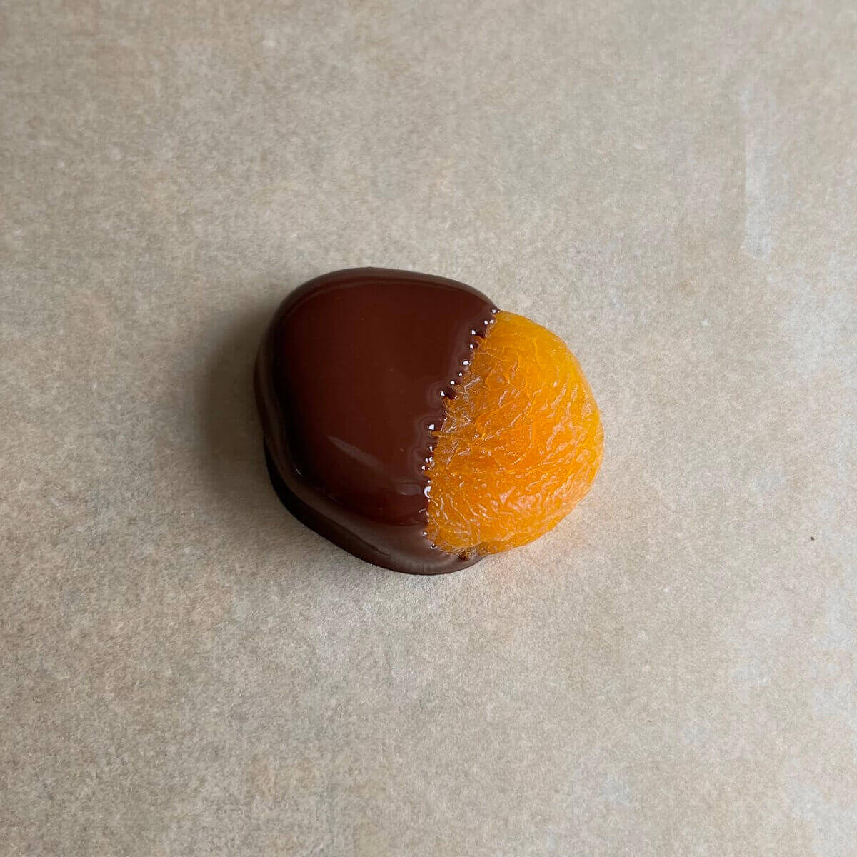 A dried apricot dipped in melted chocolate.