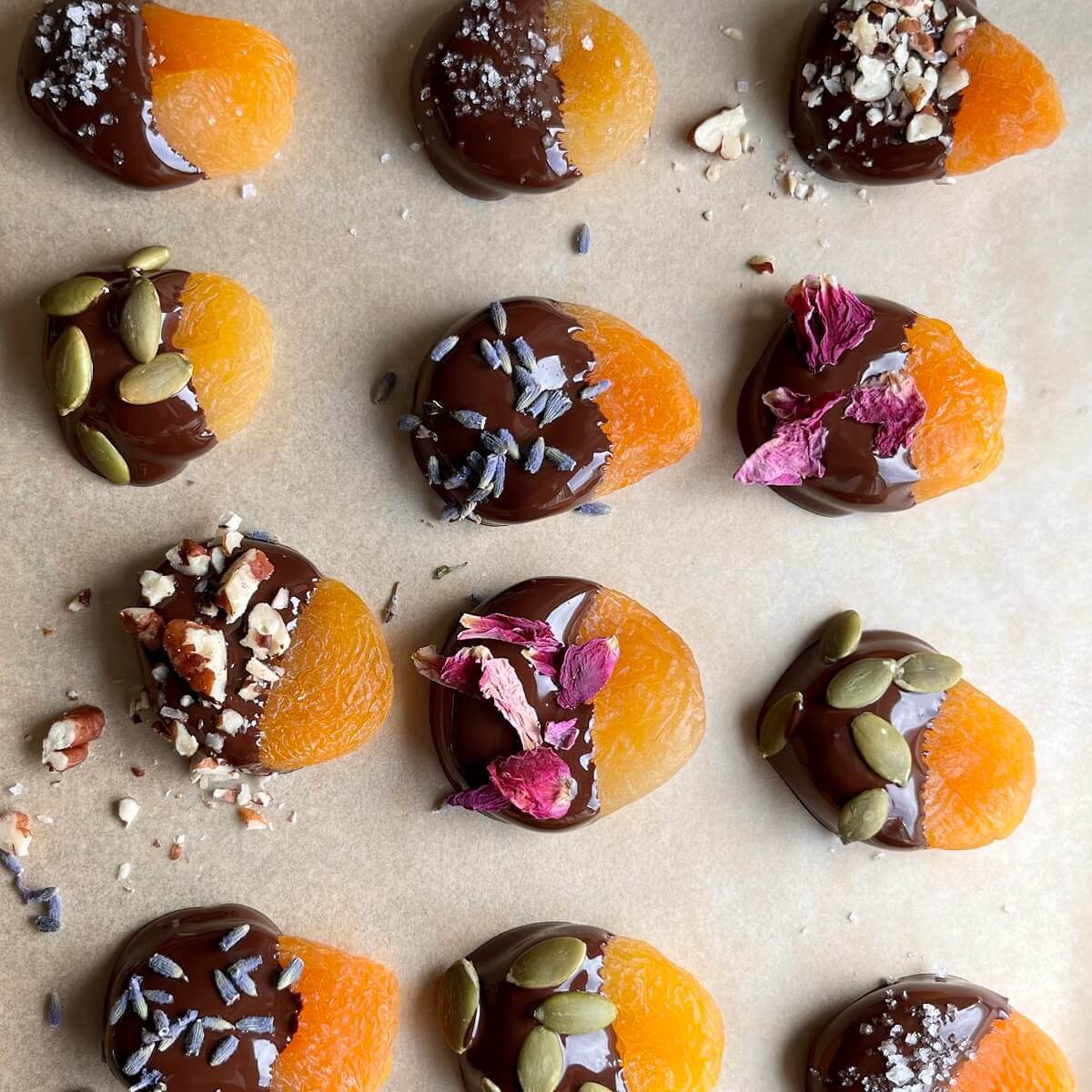 Chocolate coated apricots on a sheet pan lined with parchment paper.