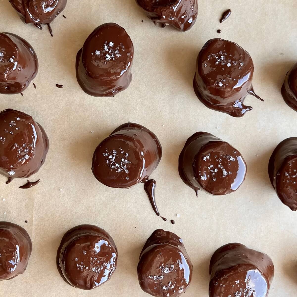 Chocolate coated banana slices on a sheet pan lined with parchment paper.