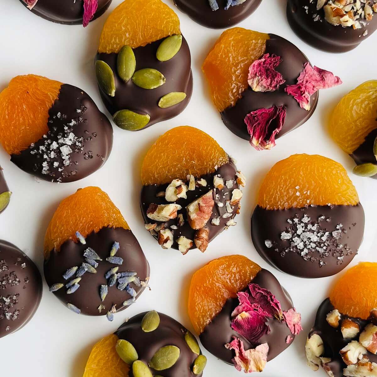 Chocolate covered apricots on a white plate.