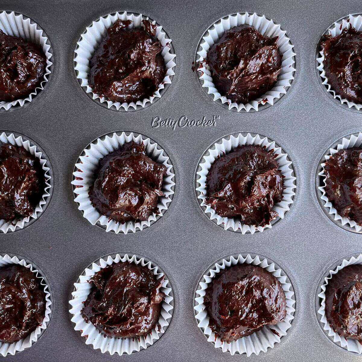 Chocolate raspberry mixture portions in a mini muffin pan.
