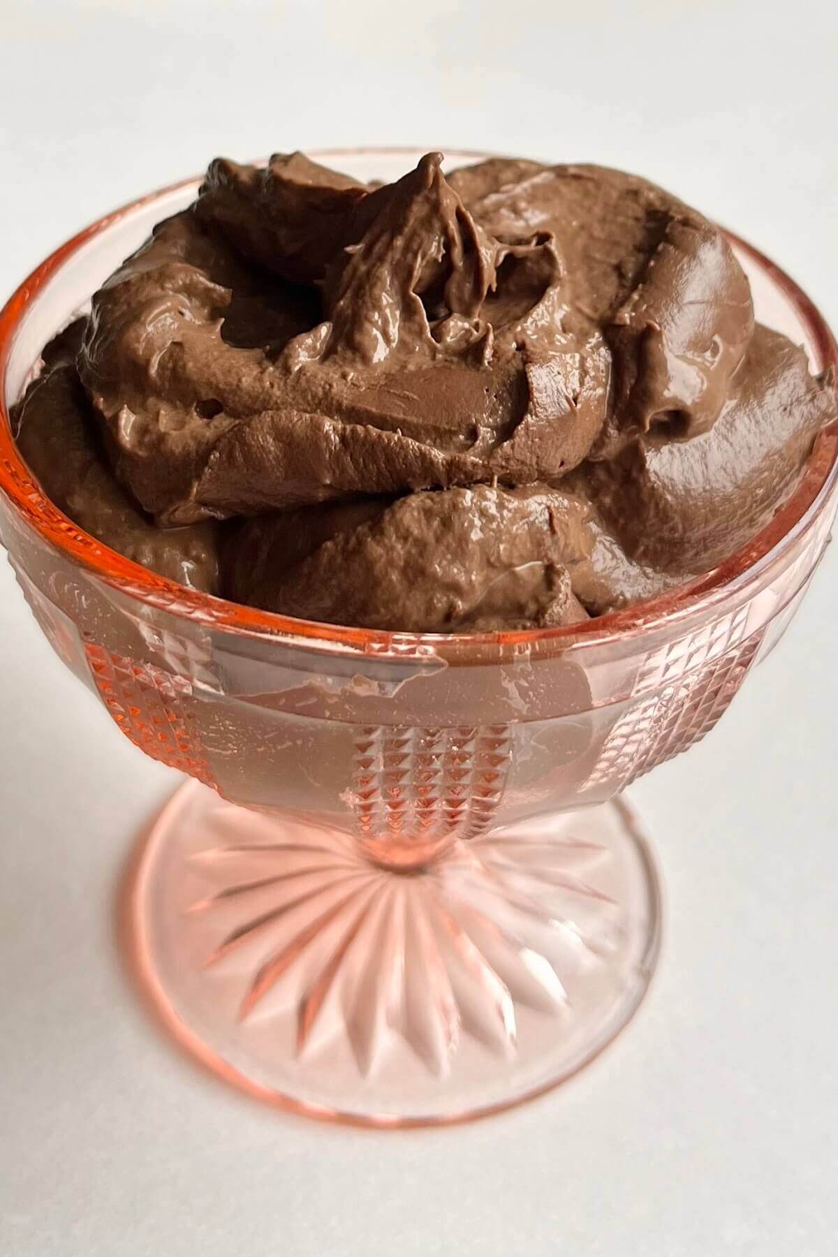 A serving of chocolate mousse in a pink glass dish.