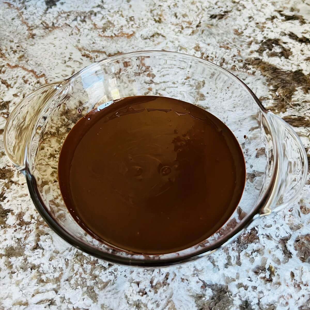 Melted dark chocolate and peanut butter in a glass bowl.