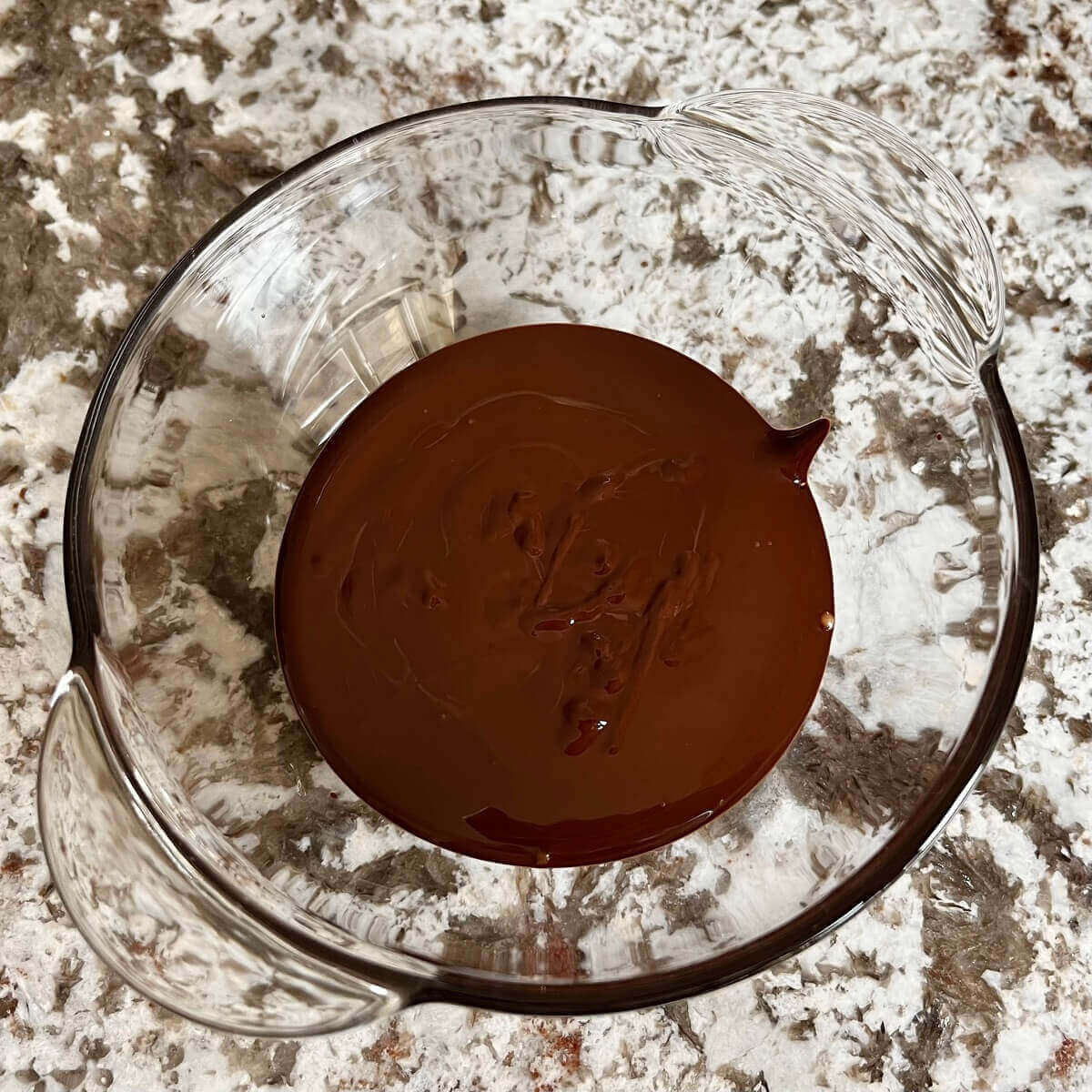 Melted warm dark chocolate in a glass bowl.