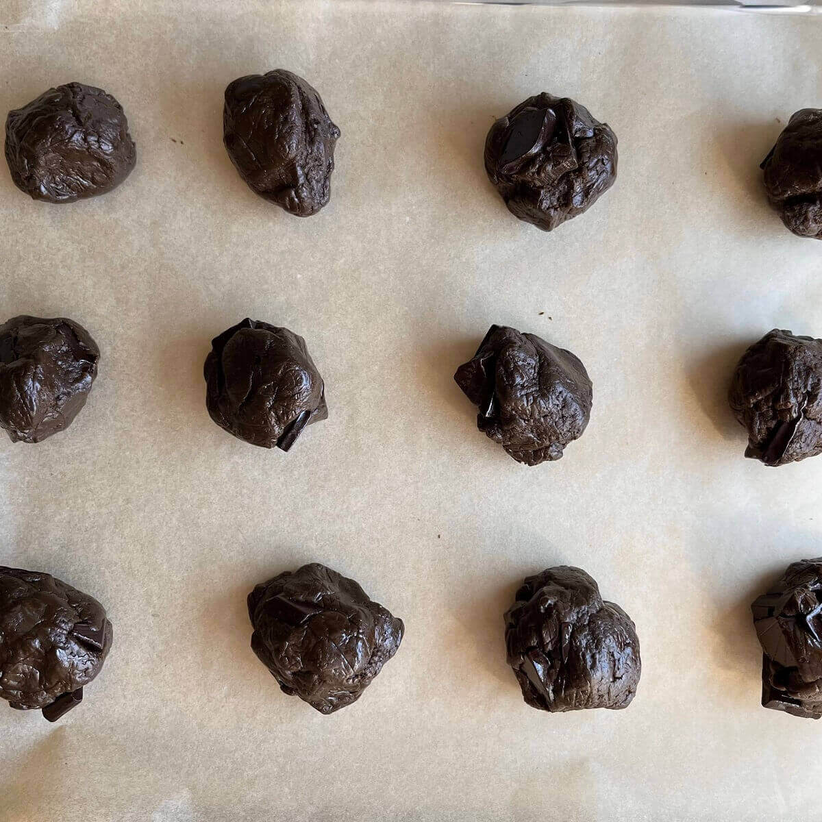 Protein cookie dough balls on a sheet pan lined with parchment paper.
