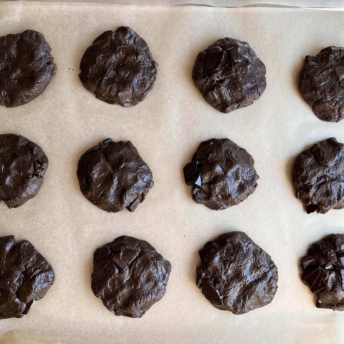 Raw protein cookies on a sheet pan lined with parchment paper.