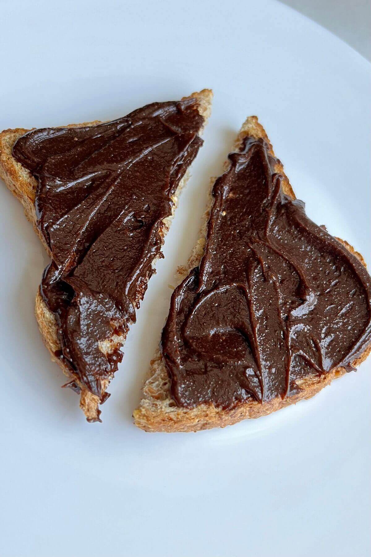 Toast slathered in carob frosting on a white plate.