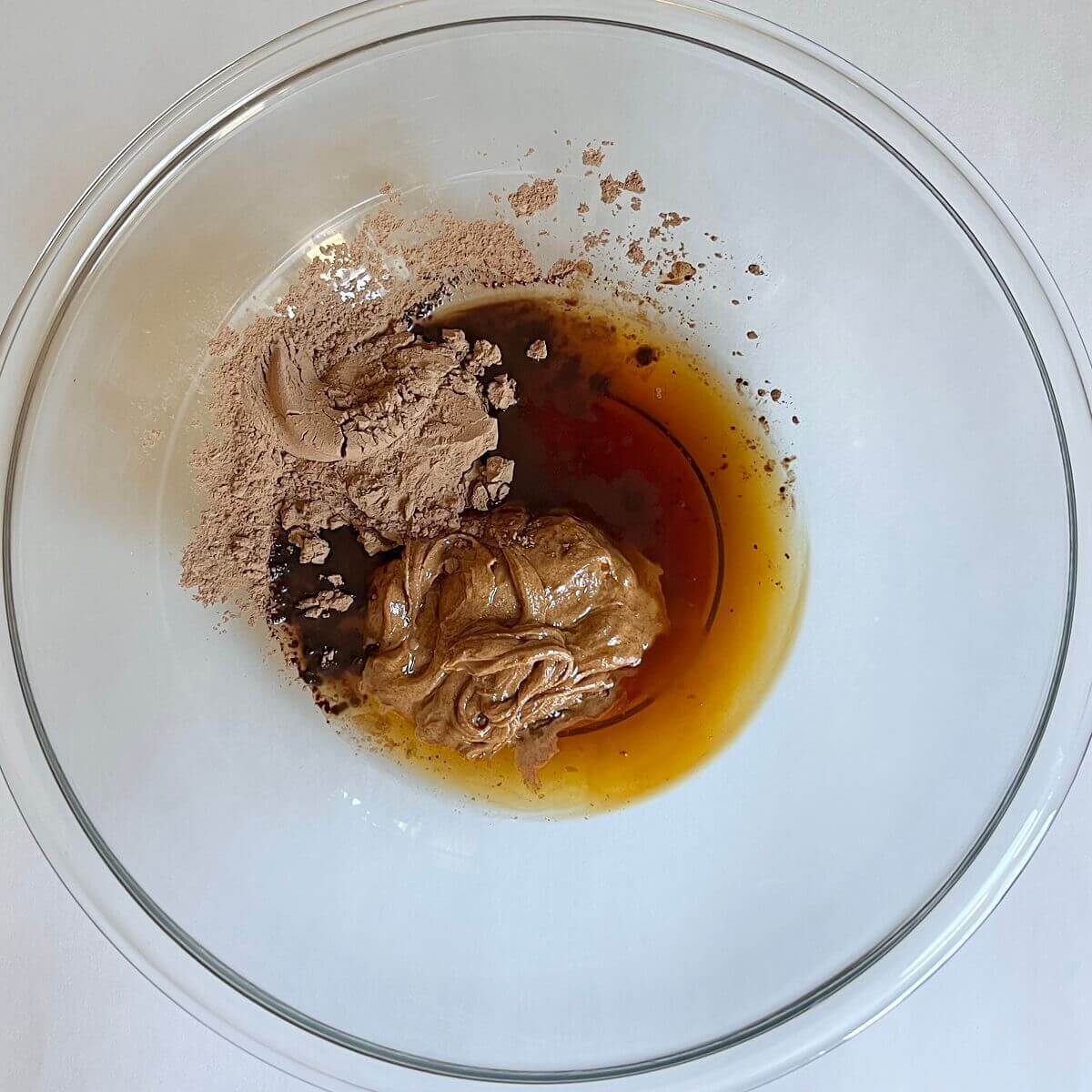 Unmixed ingredients for carob frosting in a glass bowl.