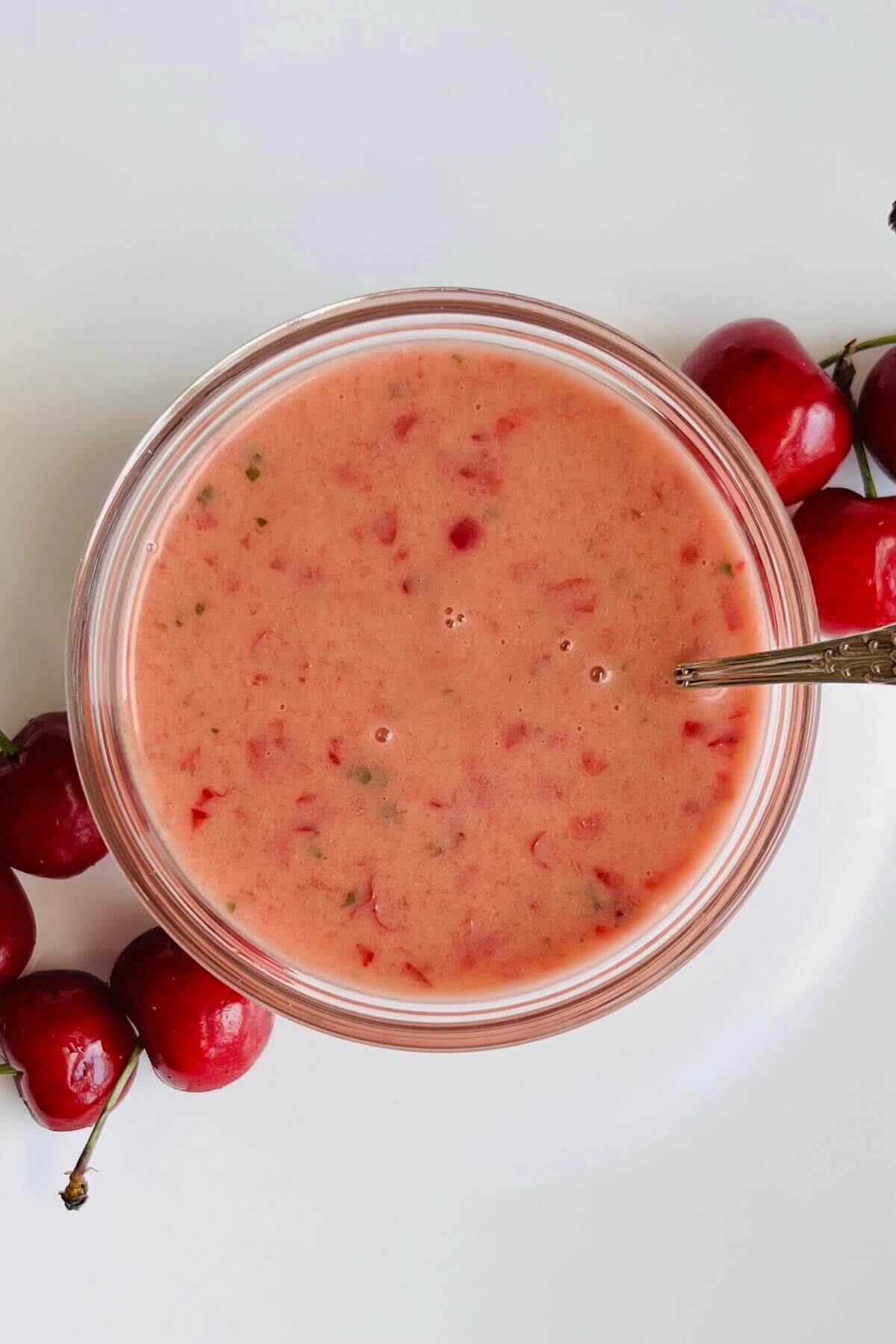 Cherry salad dressing in a bowl next to some fresh cherries.
