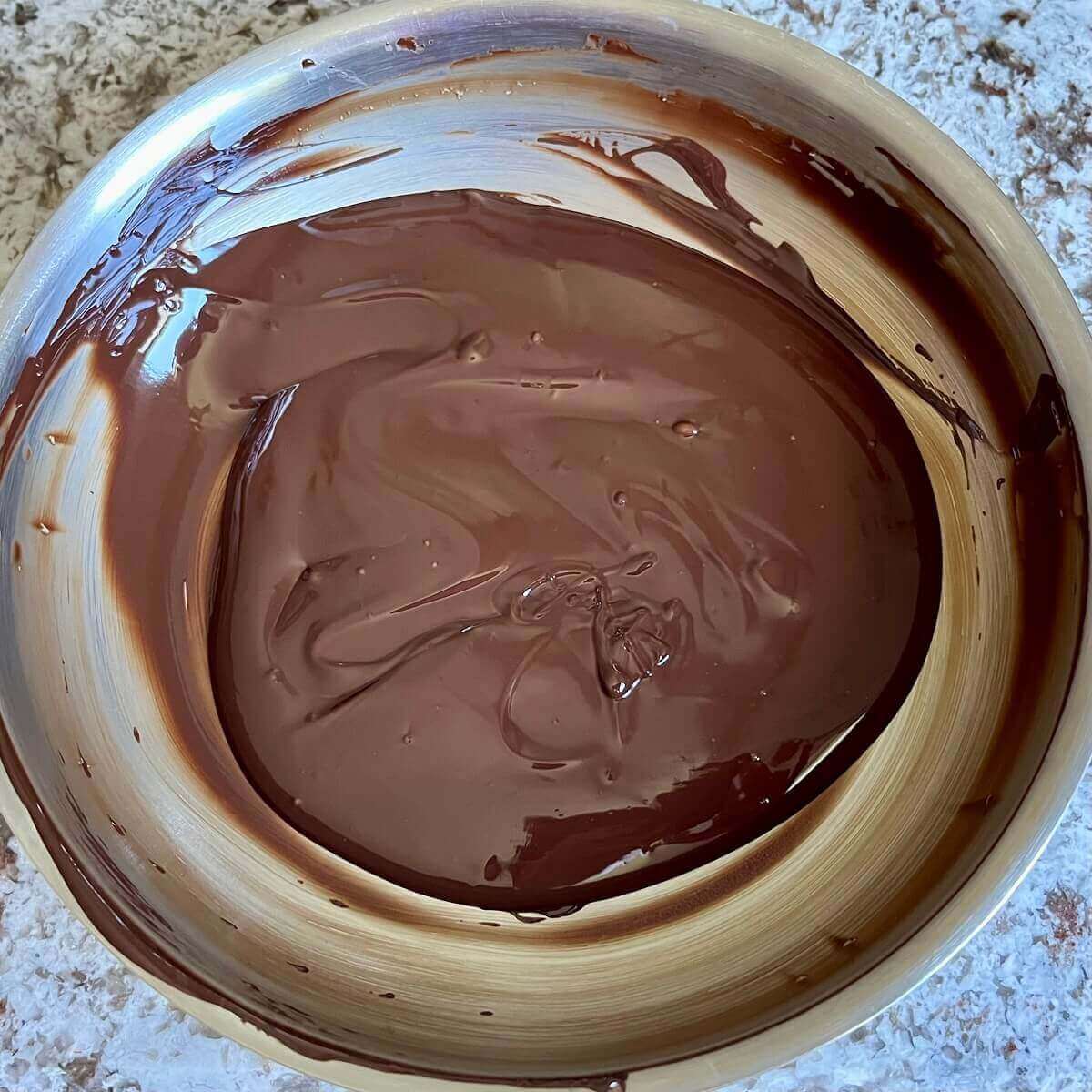 Melted dark chocolate in a steel pan.