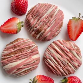 Strawberry cookies on a white plate with fresh strawberries.