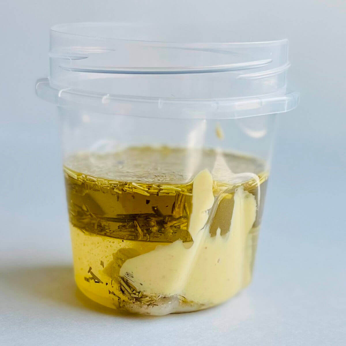 Ingredients for rosemary dressing in a plastic container.
