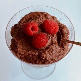 Raspberry chocolate mousse in a glass dish with an antique silver spoon.