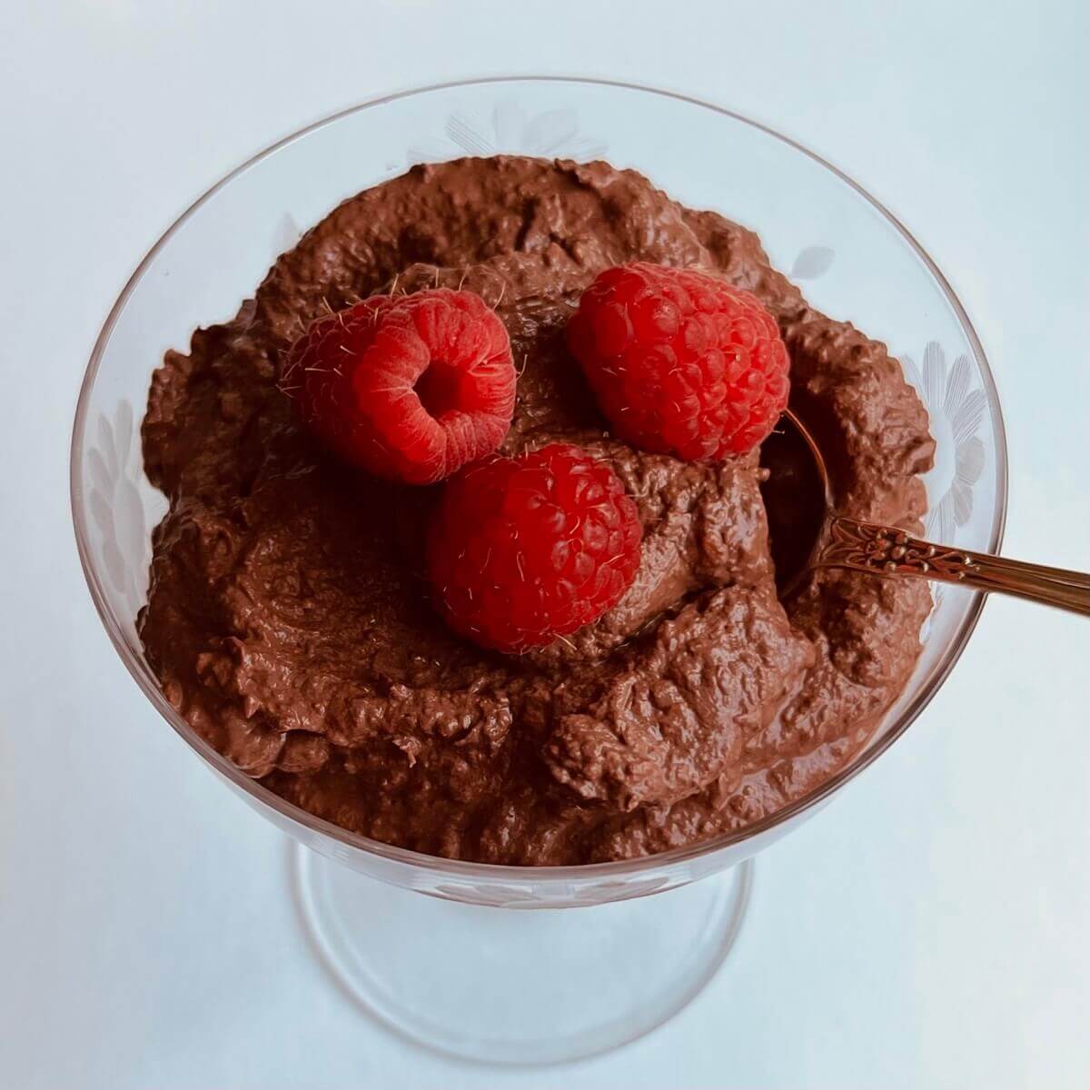 Chocolate mousse in a glass dish with an antique silver spoon.