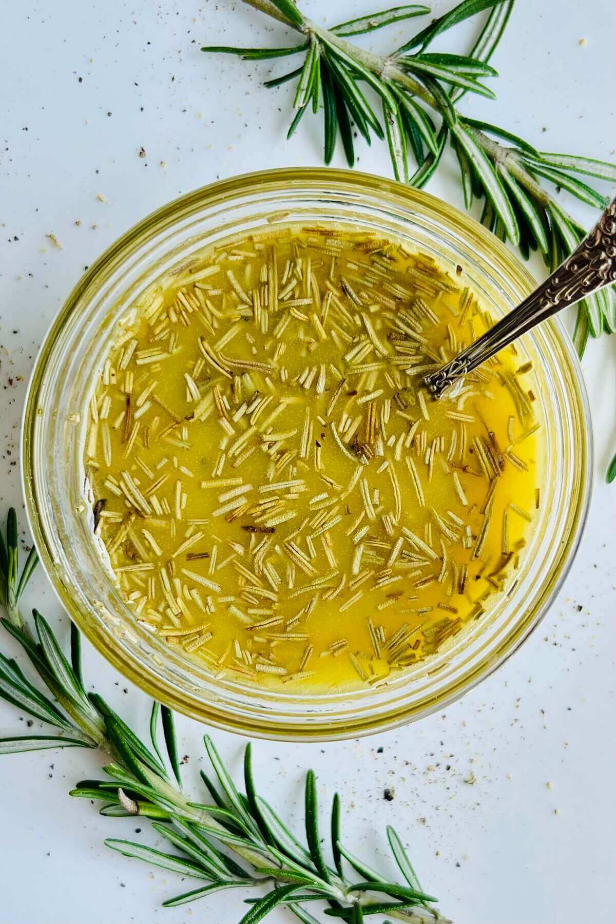 Rosemary salad dressing in a glass bowl with a silver spoon.