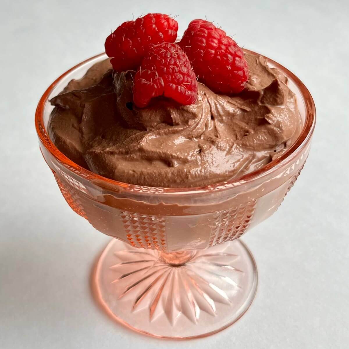 Vegan dark chocolate mousse in a pink glass dish.