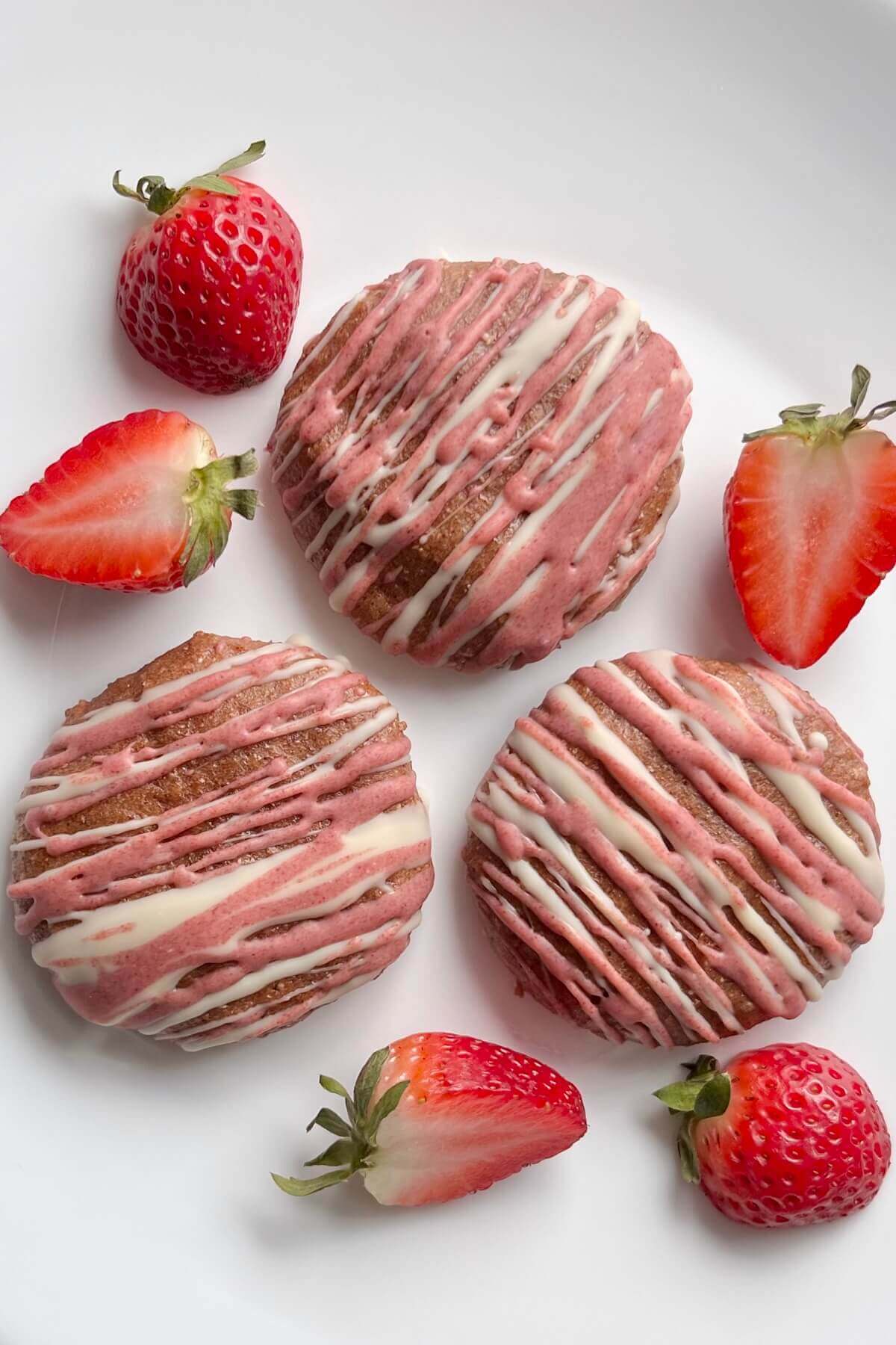 Strawberry cookies surrounded by fresh strawberries.