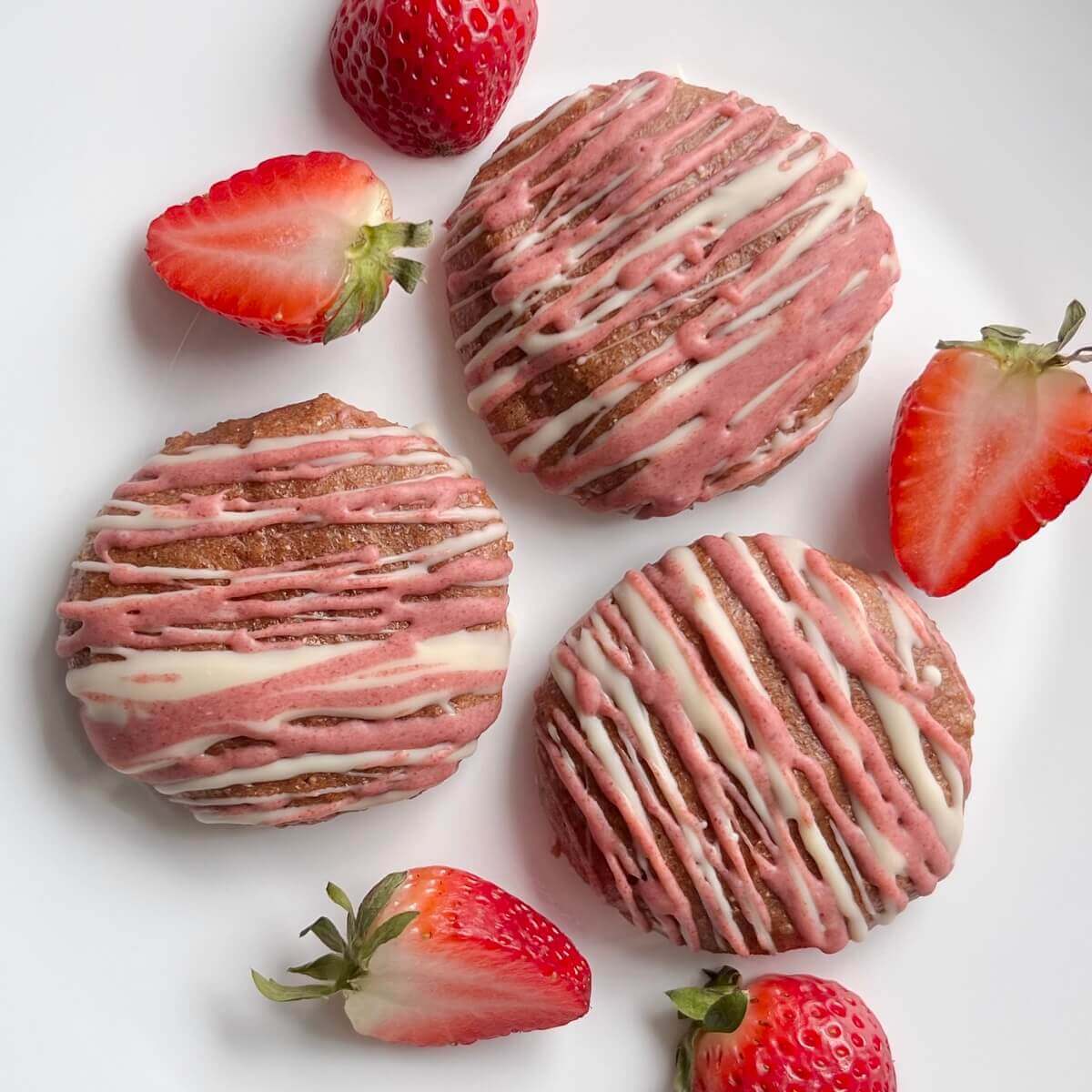 Vegan cookies surrounded by fresh strawberries on a white plate.