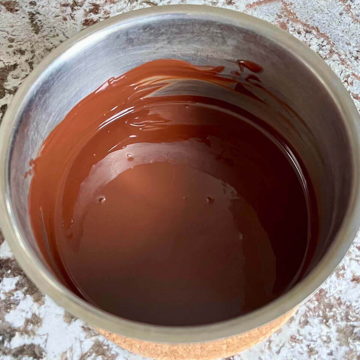 Warm dark chocolate melted in a steel pot.