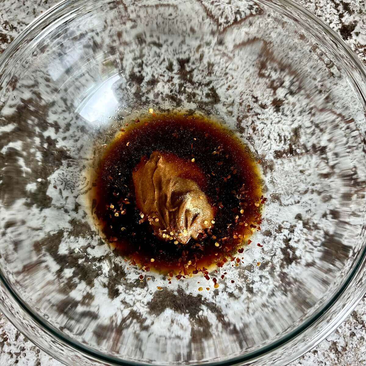 Ingredients for almond butter pasta sauce in a glass bowl.