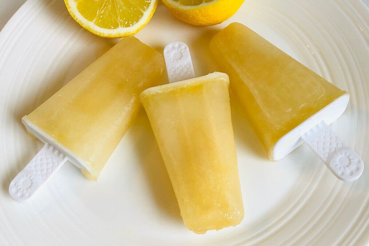 Three lemonade ice pops on a white plate.