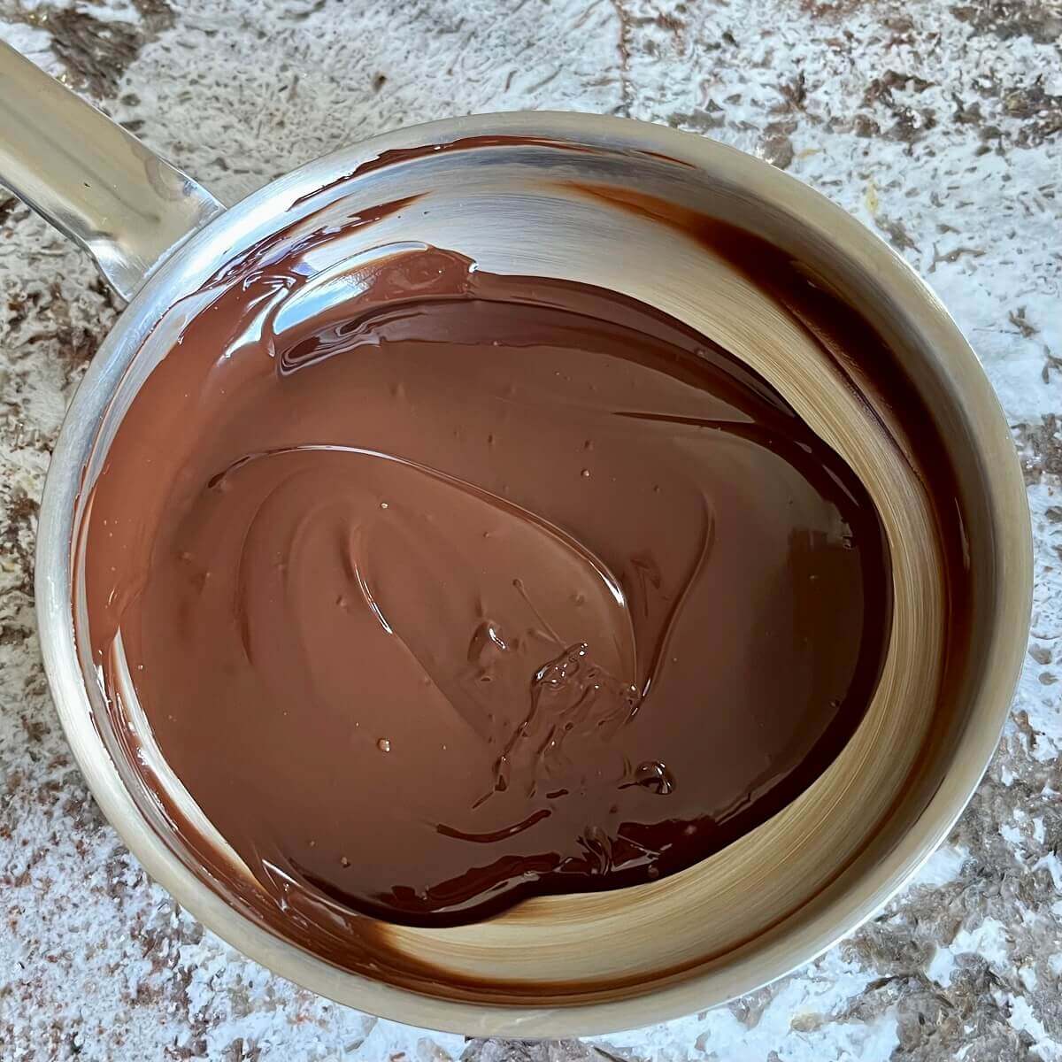 Melted dark chocolate for fudge in a steel pan.