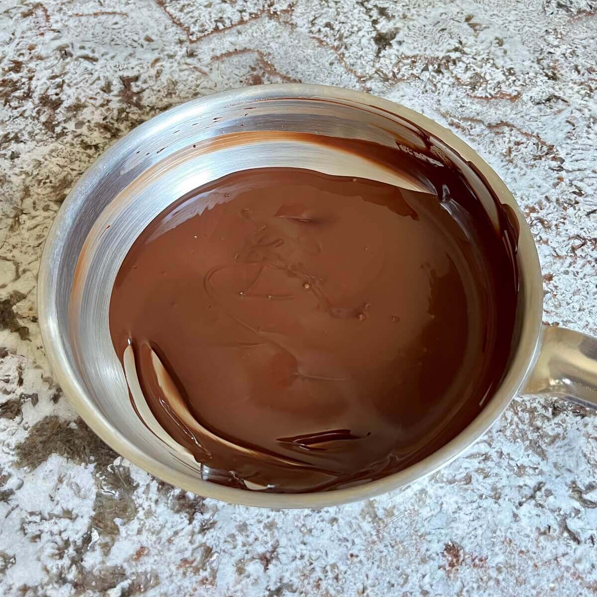 Melted dark chocolate in a steel pan.