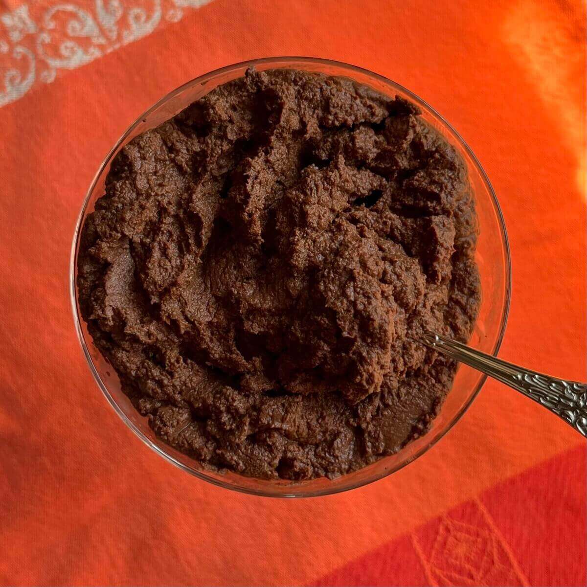 Chocolate mousse in a glass dish with a silver spoon.