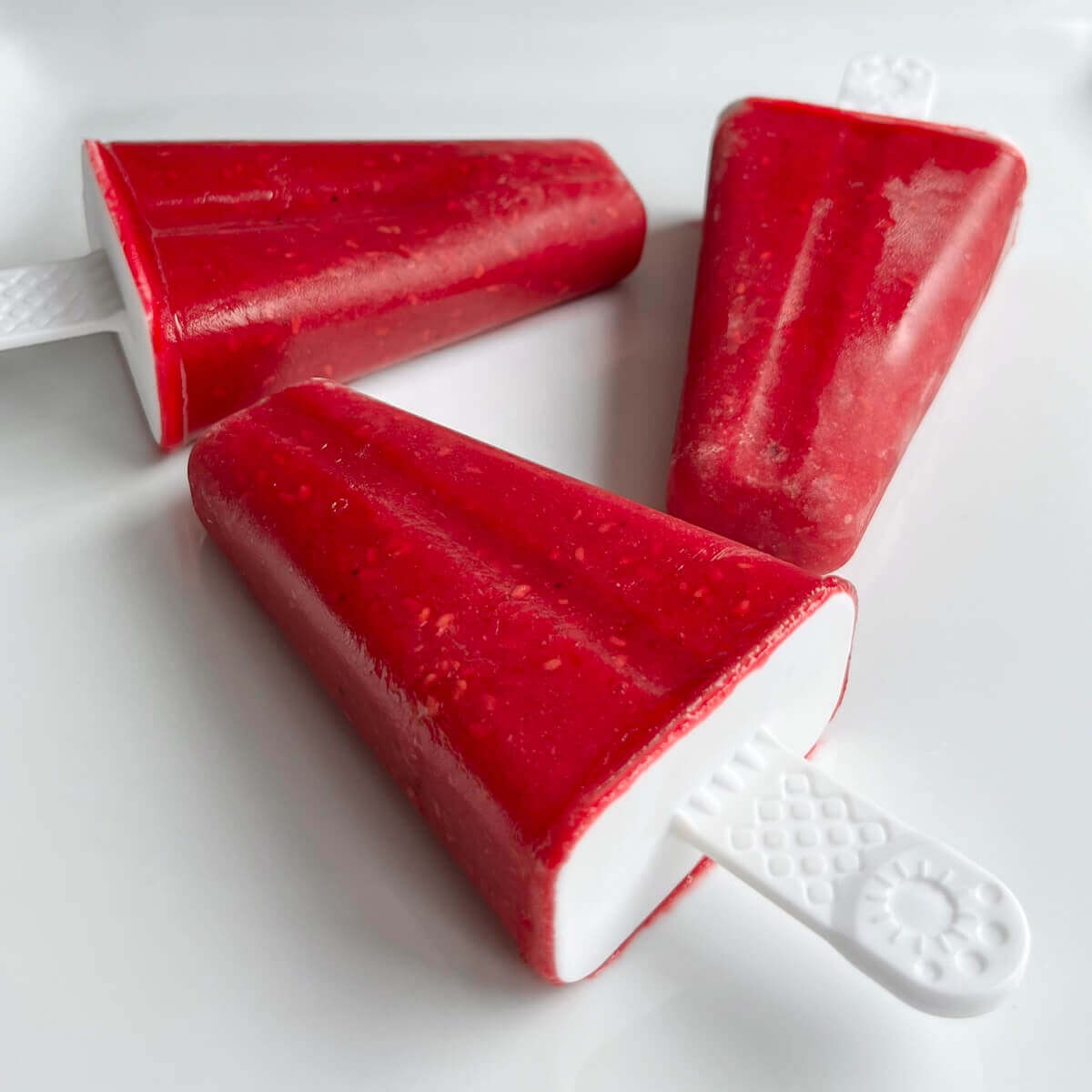 Three popsicles on a white plate.