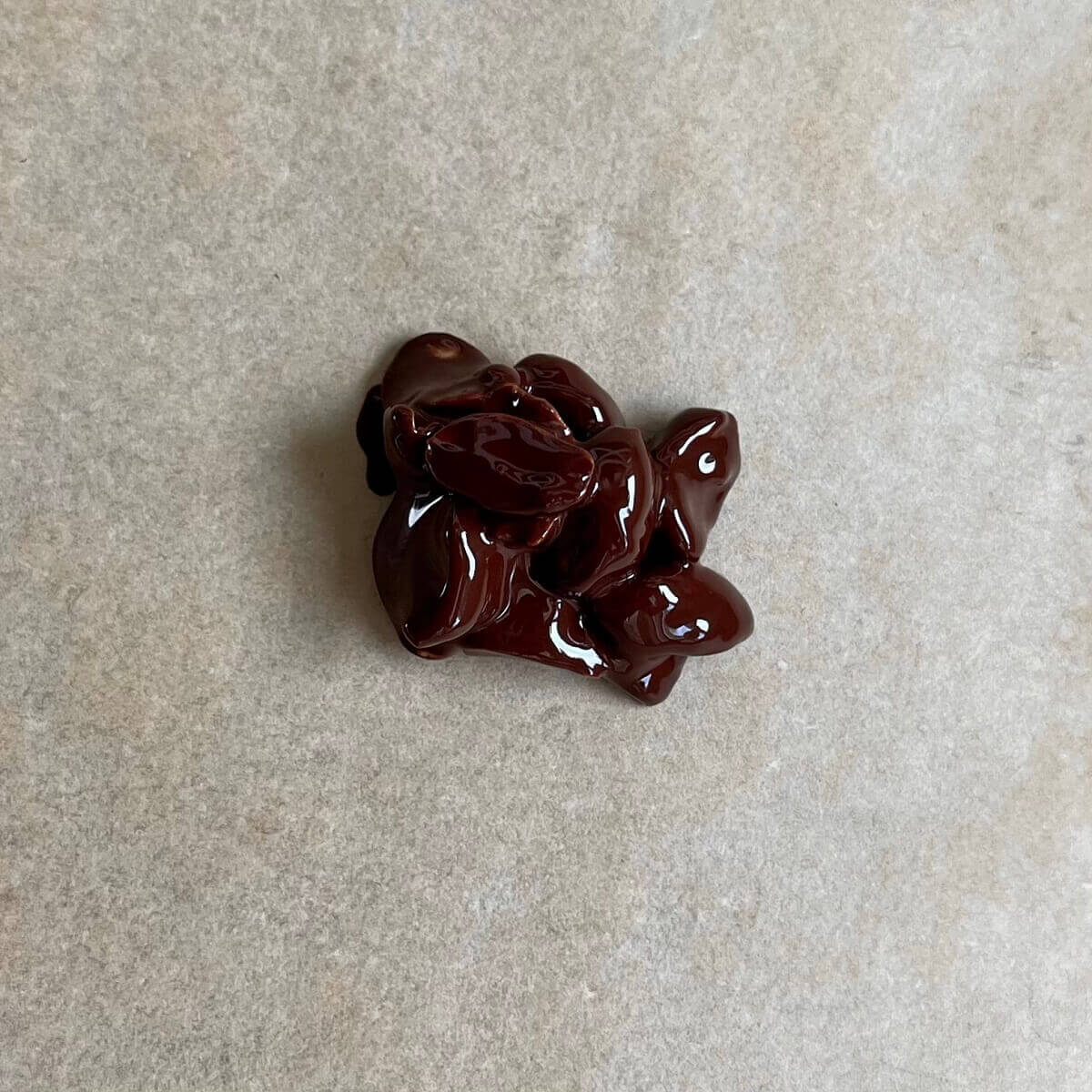 A cluster of chocolate covered peanuts on a piece of parchment paper.