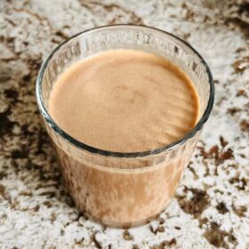 A glass of pea protein smoothie on a granite countertop.