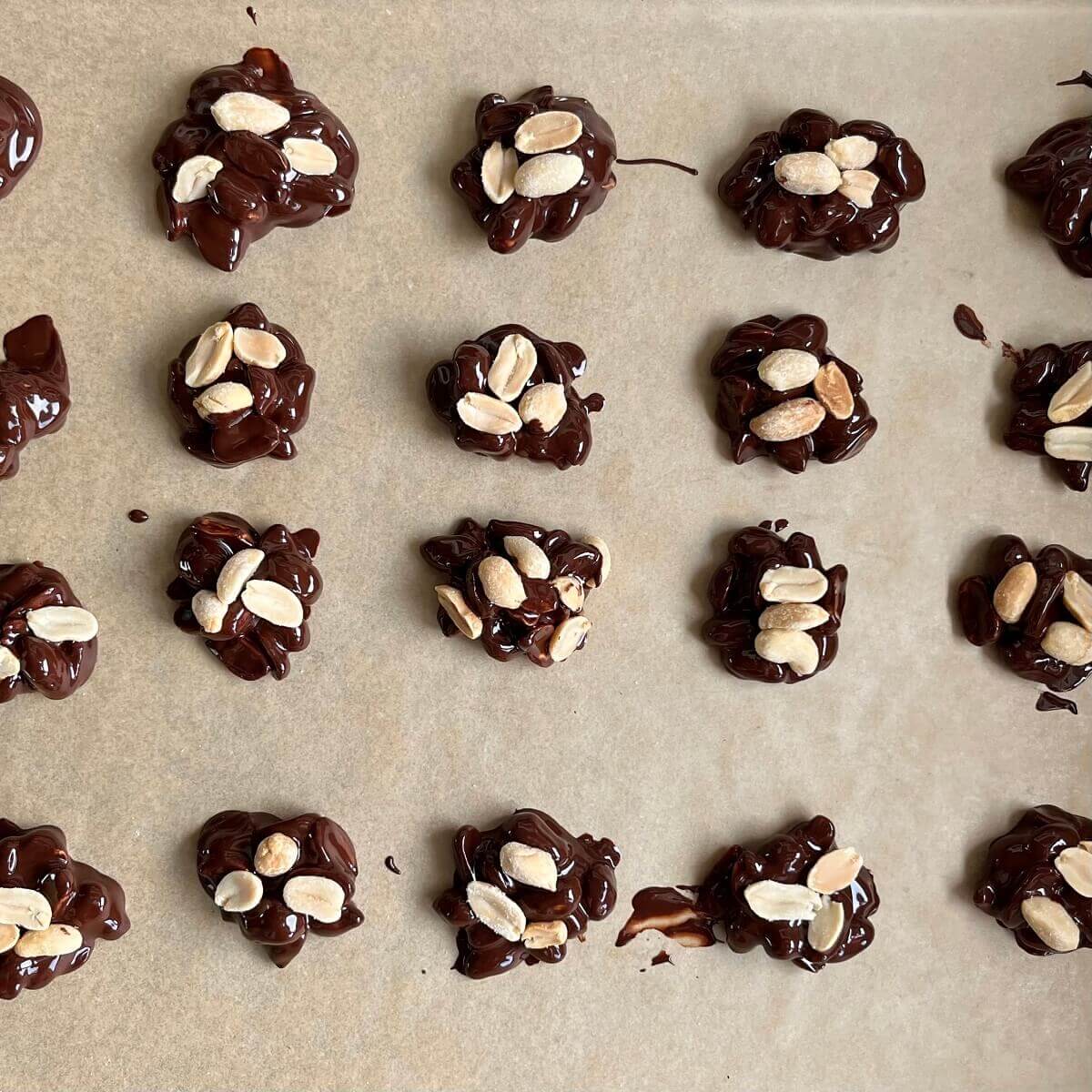 Peanut chocolate treats on a sheet pan lined with parchment paper.