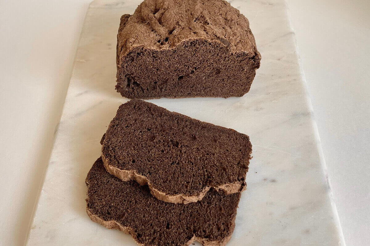 A loaf of bread made with buckwheat flour on a marble cutting board.